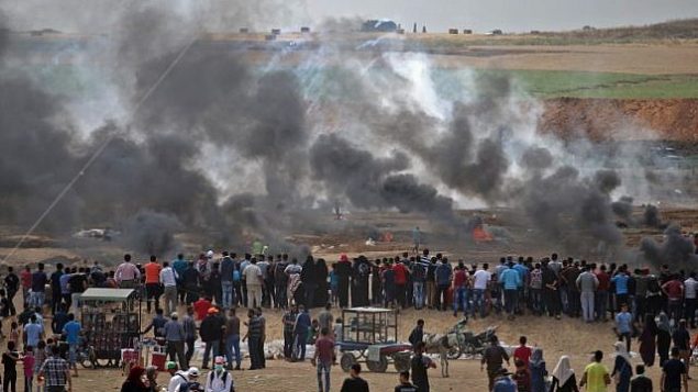 متظاهرون فلسطينيون ينظرون إلى الغاز المسيل للدموع والدخان المتصاعد من إطارات محترقة، شرقي مدينة غزة في 14 مايو، 2018.
(AFP PHOTO / Mohammed ABED) متظاهرون فلسطينيون ينظرون إلى الغاز المسيل للدموع والدخان المتصاعد من إطارات محترقة، شرقي مدينة غزة في 14 مايو، 2018.
(AFP PHOTO / Mohammed ABED)