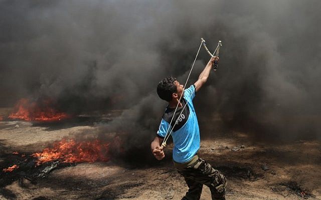 شاب فلسطيني يستخدم المقلاع خلال مواجهات مع القوات الإسرائيلية بالقرب من حدود غزة وإسرائيل شرقي مدينة خان يونس، 14 مايو، 2018. (AFP PHOTO / SAID KHATIB) شاب فلسطيني يستخدم المقلاع خلال مواجهات مع القوات الإسرائيلية بالقرب من حدود غزة وإسرائيل شرقي مدينة خان يونس، 14 مايو، 2018. (AFP PHOTO / SAID KHATIB)