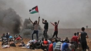 فلسطينيون يلوحون بعلمهم خلال مظاهرات بالقرب من الحدود بين اسرائيل وقطاع غزة، 14 مايو 2018 (AFP PHOTO / MOHAMMED ABED)