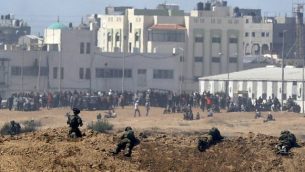 صورة تم التقاطها في 14 مايو، 2018 من كيبوتس ناحال عوز في جنوبي إسرائيل عبر الحدود مع غزة لجنود إسرائيليين ومتظاهرين فلسطينيين يحتشدون بالقرب من السياج الحدودي مع إسرائيل. (AFP/JACK GUEZ)
