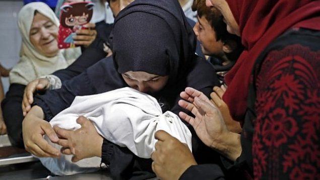 والدة ليلى الغندور، طفلة رضيعة فلسطينية تبلغ من العمر 8 أشهر التي توفيت جراء استنشاقها للغاز المسيل للدموع، بحسب وزارة الصحة التابعة لحركة حماس في غزة، تختضن جثة طفلتها في مكان حفظ الجثث في مستشفى ’الشفاء’ في مدينة غزة في 15 مايو، 2018. في 16 مايو، قالت الوزارة إنه لم يتم تحديد سبب الوفاة بصورة قاطعة. (AFP/Thomas Coex)