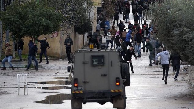 صورة توضيحية: شبان فلسطينيون يرشقون حجارة باتجاه قوات الامن الإسرائيلية خلال عملية عسكرية في مدينة جنين في الضفة الغربية، 18 يناير 2018 (AFP/Jaafar Ashtiyeh)