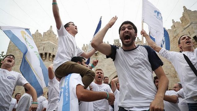 الاف اليهود يلوةحون بالاعلام الإسرائيلية خلال الاحتفال ب’يوم القدس’ في مسيرة تمر بباب العامود في البلدة القديمة في القدس بطريقهم الى حائط المبكرى، 13 مايو 2018 (Yonatan Sindel/Flash90)