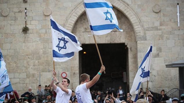 الاف اليهود يلوحون بالاعلام الإسرائيلية خلال الاحتفال ب’يوم القدس’ في مسيرة تمر بباب العامود في البلدة القديمة في القدس بطريقهم الى حائط المبكى، 13 مايو 2018 (Yonatan Sindel/Flash90)