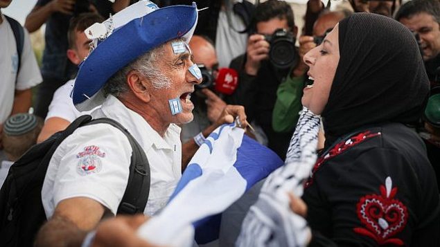 رجل يهودي يحمل علم اسرائيلي يتشاجر مع امرأة عربية مع احتفال الالاف ب’يوم القدس’ في ذكرى توحيد المدينة خلال حرب 1967، 13 مايو 2018 (Yonatan Sindel/Flash90)