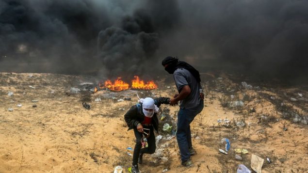 متظاهرون فلسطينيون خلال اشتباكات مع القوات الإسرائيلية بالقرب من الحدود بين اسرائيل وقطاع غزة في رفح، 14 مايو 2018 (Abed Rahim Khatib/Flash90)