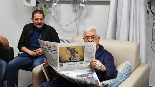 رئيس السلطة الفلسطينية محمود عباس يتماثل إلى الشفاء في المستشفى ويقرأ صحيفة يظهر على صفحتها الأخيرة رسم كاريكاتير لجندي إسرائيلي يقوم بتسميم طفلة فلسطينية، 22 مايو، 2018. (وكالةالأنباء الفلسطينية ’وفا’)