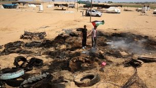 فلسطينيون يتفحصون كومة من الإطارات تشير التقارير إلى أن الطائرات الإسرائيلية اشعلت فيها النيران بالقرب من الحدود مع إسرائيل شرق رفح جنوب قطاع غزة، قبيل المواجهات الأسبوعية في 8 يونيو / حزيران 2018. (AFP Photo / Said Khatib)