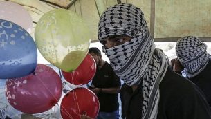 محتجون فلسطينيون يعدون بالونات محملة بمواد حارقة لإطلاقها باتجاه إسرائيل، عند حدود غزة إسرائيل في البريج، وسط قطاع غزة، 14 يونيو، 2018.  (AFP/Mahmud Hams)