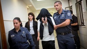 شرطي حرس الحدود بن درعي، الذي أدين في وقت لاحق بقتل فتى فلسطيني يبلغ من العمر 17 عاما خلال احتجاجات في بلدة بيتونيا في الضفة الغربية في عام 2014، يغطي وجهه خلال دخوله إلى قاعة المحكمة المركزية في القدس، 7 ديسمبر، 2014. (Miriam Alster/Flash90)