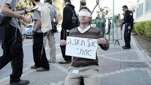 ناشط من اليمين يحمل لافتة كُتب عليها "لا تعذبني" خارج مبنى المحكمة في مدينة بيتح تيكفا حيت تجرى محاكمة المشتبه بهما في هجوم دوما، 28 ديسمبر، 2015. Neuberg/Flash90)