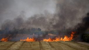 طواقم الإطفاء تعمل على إخماد النيران في حقل قمح ناجم عن تطيير طائرات ورقية من قبل متظاهرين فلسطينيين، بالقرب من الحدود مع قطاع غزة، 30 مايو، 2018.(Yonatan Sindel/Flash90)