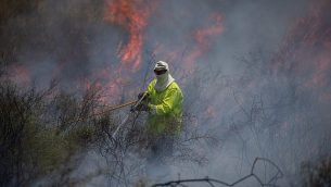 رجال الإطفاء يعملون على إخماد النار في حقل بعد اندلاع حريق فيه ناجم عن طائرات ورقية أطلقها فلسطينيون في قطاع غزة، بالقرب من الحدود مع قطاع غزة، 5 يونيو، 2018. (Yonatan Sindel/Flash90)