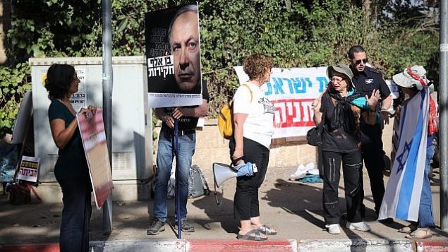 متظاهرون ضد رئيس الوزراء بنيامين نتنياهو خارج مقر إقامته في القدس، قبيل وصول محققين من الشرطة إلى مقره، في 12 يونيو 2018. (Hadas Parush/Flash90)