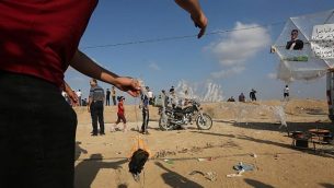 متظاهر فلسطيني يستعد لبربط مواد حارقة بطائرة ورقية قبل إطلاقها باتجاه إسرائيل في 13 يوليو، 2018 خلال مظاهرة عند السياج الحدودي بين غزة وإسرائيل شرقي مدينة غزة. (AFP PHOTO / MAHMUD HAMS)