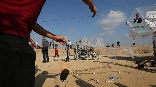 متظاهر فلسطيني يستعد لبربط مواد حارقة بطائرة ورقية قبل إطلاقها باتجاه إسرائيل في 13 يوليو، 2018 خلال مظاهرة عند السياج الحدودي بين غزة وإسرائيل شرقي مدينة غزة. (AFP PHOTO / MAHMUD HAMS) متظاهر فلسطيني يستعد لبربط مواد حارقة بطائرة ورقية قبل إطلاقها باتجاه إسرائيل في 13 يوليو، 2018 خلال مظاهرة عند السياج الحدودي بين غزة وإسرائيل شرقي مدينة غزة. (AFP PHOTO / MAHMUD HAMS)
