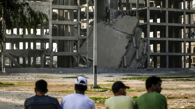 شبان فلسطينيين ينظرون الى مبنى دمرته غارة جوية اسرائيلية في مخيم الشاطئ في شمال قطاع غزة، 14 يوليو 2018 (AFP PHOTO / MAHMUD HAMS)