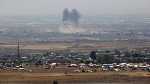 صورة التقطت من الطرف الإسرائيلي من مرتفعات الجولان تظهر الدخان يتصاعد فوق مباني خلال غارة جوية بالقرب من مخيم نازظحين سوريين في محافظة درعا جنوب سوريا، 18 يوليو 2018 (JALAA MAREY/AFP)