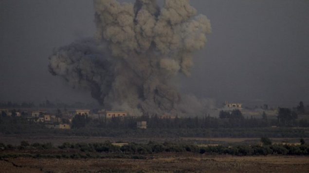 صورة التقطت من الطرف الإسرائيلي في مرتفعات الجولان تظهر الدخان يتصاعد من مباني في الطرف السوري من الحدود خلال غارات جوية سورية في محافظة القنيطرة، 25 يوليو 2018 (AFP / JALAA MAREY)