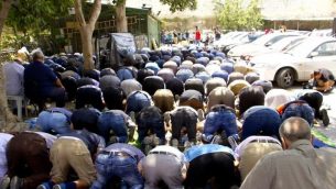 يشارك المصلين المسلمين في صلاة الظهر في موقف للسيارات بالقرب من بوابة الأسباط في مدينة القدس القديمة، رافضين الدخول إلى منطقة الحرك للوصول إلى المسجد الأقصى في الداخل، 25 يوليو 2017. (دوف ليبر / تايمز أوف إسرائيل)
