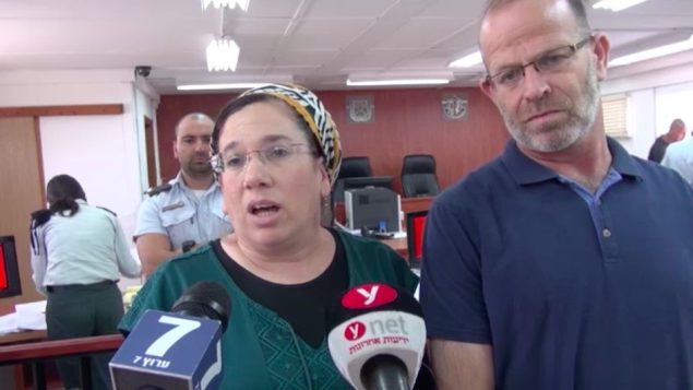 نيريت زامورا تتحدث مع صحفيين داخل محكمة يهودا العسكرية، الى جانب زوجها، قبل محاكمة منفذ هجوم ضدها، 16 يوليو 2018 (Screen capture/Israel National News) نيريت زامورا تتحدث مع صحفيين داخل محكمة يهودا العسكرية، الى جانب زوجها، قبل محاكمة منفذ هجوم ضدها، 16 يوليو 2018 (Screen capture/Israel National News)