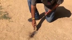 رجل يتفقد موقع سقوط بالون في ساحة روضة أطفال في المجلس الإقليمي سدون خنيغف في 17 يوليو، 2018.  (لقطة شاشة: القناة 10)