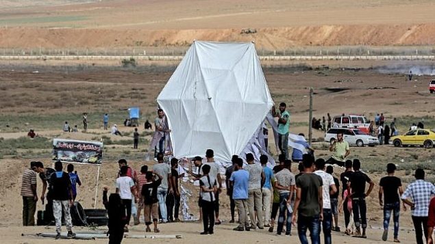 فلسطينيون يستعدون لإطلاق طائرة ورقية بالقرب من الحدود بين غزة وإسرائيل، شرقي جباليا، 3 أغسطس، 2018. (AFP/ MAHMUD HAMS) فلسطينيون يستعدون لإطلاق طائرة ورقية بالقرب من الحدود بين غزة وإسرائيل، شرقي جباليا، 3 أغسطس، 2018. (AFP/ MAHMUD HAMS)