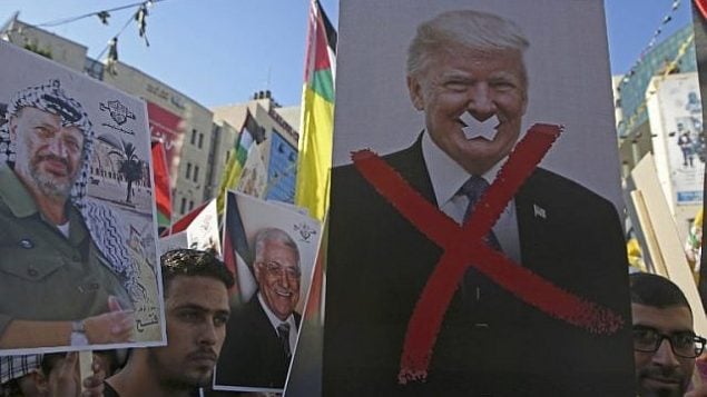 في هذه الصورة من 17 يوليو، 2018، يحمل متظاهرون فلسطينيون صورا للزعيم الفلسطيني الراحل ياسر عرفات والرئيس الأمريكي دونالد ترامب خلال مسيرة لدعم حركة ’فتح’ في مدينة نابلس في الضفة الغربية. (AFP Photo/Jaafar Ashtiyeh)
