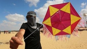 محتج فلسطيني يقوم بإطلاق طائرة ورقية محملة بمواد حارقة باتجاه إسرائيل خلال مظاهرة على الحدود مع إسرائيل، شرقي مدينة رفح في جنوب قطاع غزة، 29 يونيو، 2018. (Abed Rahim Khatib/Flash90)