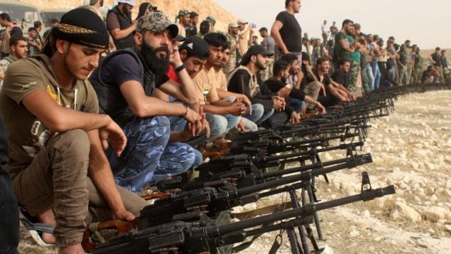 مقاتلو معارضة سوريون يجلسون خلف رشاشات خلال موكب عسكري بالقرب من مدينة درعا جنوب سوريا، 7 يونيو 2018 (Mohamad Abazeed/AFP)