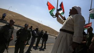 متظاهرون فلسطينيون يلوحون بالاعلام الوطنية امام جنود اسرائيليين خلال مظاهرة ضد هدم قرية خان الاحمر البدوية في الضفة الغربية، 14 سبتمبر 2018 (AFP PHOTO / ABBAS MOMANI)