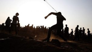 متظاهر فلسطيني يلقي حجرا  باتجاه القوات الإسرائيلية خلال مواجهات على السياج الحدودي، شرقي مدينة غزة في 28 سبتمبر، 2018. (AFP Photo/Said Khatib)