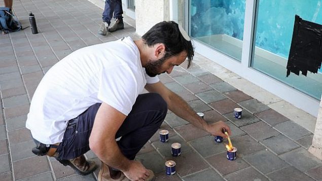 الناس يشعلون الشموع في ذكرى آري فولد، في الموقع الذي قُتل فيه في هجوم، في تقاطع غوش عتسيون، 16 سبتمبر 2018. (Gershon Elinson / FLASH90)