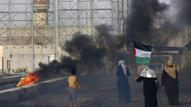 سيدة فلسطينية تحمل العلم الفلسطيني خلال مظاهرات عند معبر إيريز بين اسرائيل وشمال قطاع غزة، 3 اكتوبر 2018 (AFP/Said Khatib)
