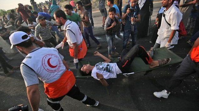 مسعفون فلسطينيون يحملون رجلا مصابا خلال مظاهرات عند معبر إيريز بين اسرائيل وشمال قطاع غزة، 3 اكتوبر 2018 (AFP/Said Khatib)