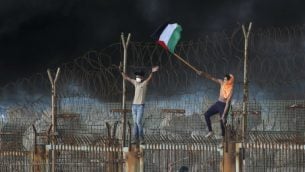 متظاهرون فلسطينيون يرفعون علم فلسطيني على مبنى حديدي خلال مظاهرة في شاطئ بالقرب من الحدود البحرية مع اسرائيل، في شمال قطاع غزة، 8 اكتوبر 2018 (Said KHATIB / AFP)