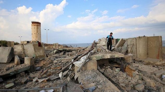 رجل فلسطيني يمشي فوق الأنقاض في أعقاب غارة جوية إسرائيلية بالقرب من مدينة رفح في جنوب قطاع غزة في أعقاب سقوط صارو خ على منزل في مدينة بئر السبع  الإسرائيلية، 17 أكتوبر، 2018. (SAID KHATIB / AFP)