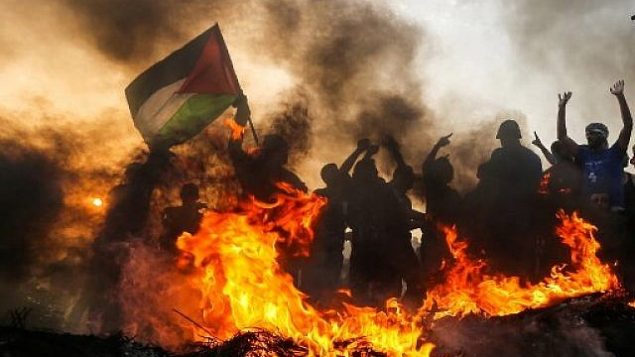 فلسطيني يلوح بعلمه خلال مظاهرة على الشاطئ قرب الحدود البحرية مع إسرائيل، في شمال قطاع غزة، في 22 أكتوبر 2018. (Mahmud Hams/AFP)