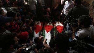 مشيعون يحملون جثامين ملفوفة بالأعلام الفلسطينية لثلاثية فتية قُتلوا في غارة جوية إسرائيلية، خلال جنازتهم في مدينة دير البلح، وسط قطا ع غزة، 29 أكتوبر، 2018. (MAHMUD HAMS / AFP)