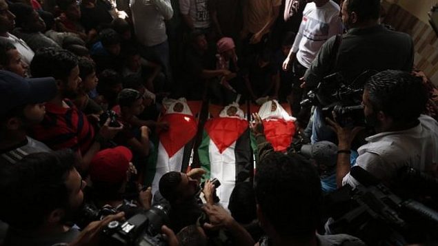مشيعون يحملون جثامين ملفوفة بالأعلام الفلسطينية لثلاثية فتية قُتلوا في غارة جوية إسرائيلية، خلال جنازتهم في مدينة دير البلح، وسط قطا ع غزة، 29 أكتوبر، 2018. (MAHMUD HAMS / AFP) مشيعون يحملون جثامين ملفوفة بالأعلام الفلسطينية لثلاثية فتية قُتلوا في غارة جوية إسرائيلية، خلال جنازتهم في مدينة دير البلح، وسط قطا ع غزة، 29 أكتوبر، 2018. (MAHMUD HAMS / AFP)