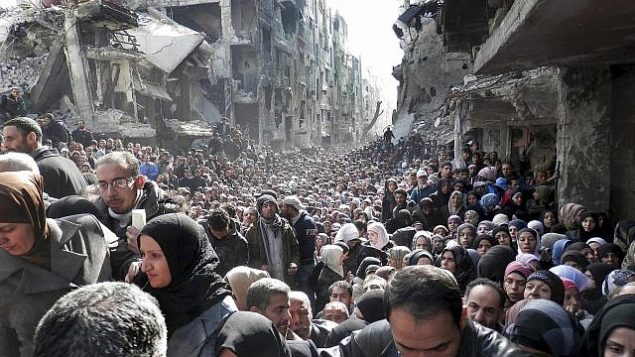 ملف - في 31 كانون الثاني / يناير 2014، تظهر صورة الملف الصادرة عن الأونروا، سكان مخيم اليرموك الفلسطيني المحاصر، يصطفون للحصول على الإمدادات الغذائية، في دمشق، سوريا (UNRWA via AP, File)