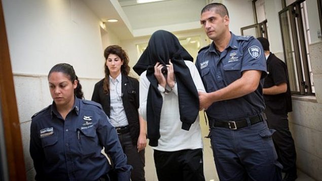 ضابط شرطة الحدود بن درعي، الذي أدين فيما بعد بقتل مراهق فلسطيني يبلغ من العمر 17 عاماً في بلدة بيتونيا بالضفة الغربية في عام 2014، يغطي وجهه أثناء دخوله جلسة استماع في محكمة مقاطعة القدس في 7 ديسمبر / كانون الأول ، 2014. (Miriam Alster/Flash90)