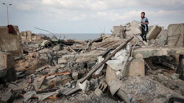 فلسطينيون يسيرون على أنقاض مبنى في أعقاب غارة جوية إسرائيلية في محيط مدينة رفح في جنوب قطاع غزة في 17 أكتوبر، 2018.  (Abed Rahim Khatib/ Flash90)