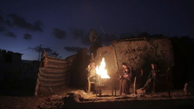 في هذه الصورة من 15 يناير، 2017، عائلة فلسطينية تحاول أن تتدفا حول النار خارج منزل من الصفيح خلال انقطاع للكهرباء في مدينة خان يونس في جنوب قطاع غزة.  (AP Photo/ Khalil Hamra)