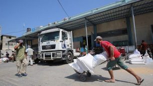 رجل فلسطيني يقول بنقل أكياس من الدقيق خارج مركز توزيع مساعدات تديره وكالة الأمم المتحدة لغوث وتشغيل اللاجئين الفلسطينيين (أونروا) في خان يونس في جنوب قطاع غزة، 4 سبتمبر، 2018. (Said Khatib/AFP)