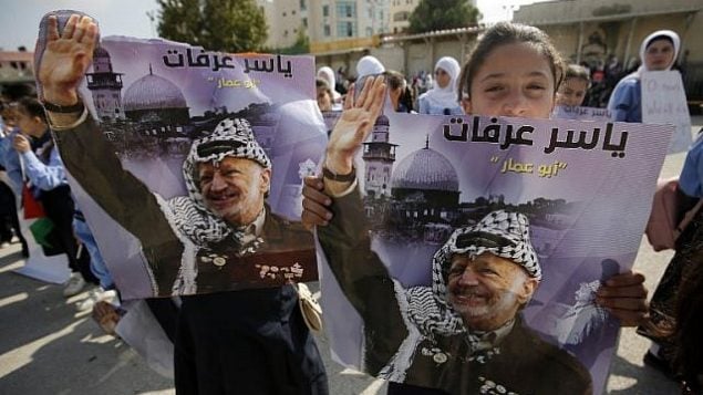 فتاة تحمل صورة الزعيم الراحل ياسر عرفات بينما يحتفل الفلسطينيون بالذكرى الرابعة عشرة لوفاته في مدينة رام الله بالضفة الغربية، في 11 نوفمبر / تشرين الثاني 2018. (ABBAS MOMANI/AFP)