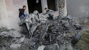 فلسطينيون يقفون بالقرب من مركبة، ورد أنه تم تدميرها في أعقاب غارة جوية إسرائيلية في خان يونس في جنوب قطاع غزة، 12 نوفمبر، 2018. (Photo by SAID KHATIB / AFP)