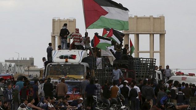 متظاهرون فلسطينيون يلوحون بالإعلام الفلسطينية أثناء ركوب شاحنة مليئة بالإطارات بالقرب من السياج الحدودي بين قطاع غزة وإسرائيل خلال مظاهرة في مدينة غزة، الجمعة، 26 أكتوبر، 2018. (AP/Adel Hana) متظاهرون فلسطينيون يلوحون بالإعلام الفلسطينية أثناء ركوب شاحنة مليئة بالإطارات بالقرب من السياج الحدودي بين قطاع غزة وإسرائيل خلال مظاهرة في مدينة غزة، الجمعة، 26 أكتوبر، 2018. (AP/Adel Hana)
