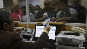موظف حكومي فلسطيني لدى حماس يوقع من اجل الحصول على 60% من اجره المتأخر بينما ينتظر اخرون، في مكتب البريد المركزي في غزة، 9 نوفمبر 2018 (AP/Adel Hana)