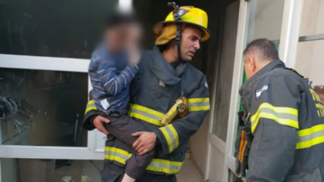 رجل إطفاء ينقذ طفلا من مبنى محترق في بيت شيمش، 15 نوفمبر، 2018.  (Israel Fire and Rescue Services)